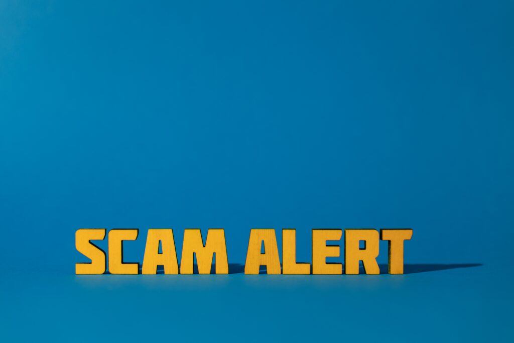 a picture of the words "scam alert" orange letters with a blue background.